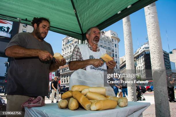 Two men cut bread in half to make the 'choripanes' during the 'Parrillazo' to as part of a protest against the ban on food carts near soccer venues...