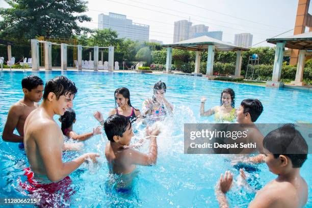 group of teenage friends having fun in swimming pool - stock image - boy-with-a-girl-playing-at-the-poolside stock pictures, royalty-free photos & images