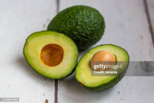 whole and sliced avocado - speisen und getränke stock pictures, royalty-free photos & images