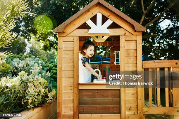 young girl playing in play house in backyard - casa de brinquedo imagens e fotografias de stock