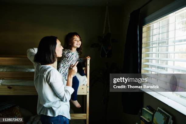 smiling mother and daughter looking out window of bedroom - bunk beds for 3 stock-fotos und bilder