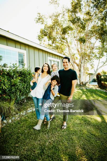 portrait of smiling family standing in front yard of home - 9 12 weeks ストックフォトと画像