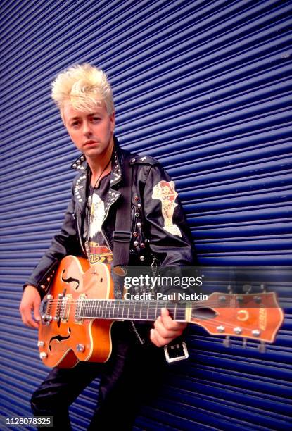 Portrait of American Rockabilly and Rock musician Brian Setzer, of the group Stray Cats, as he poses with his guitar, backstage at the Marcus...