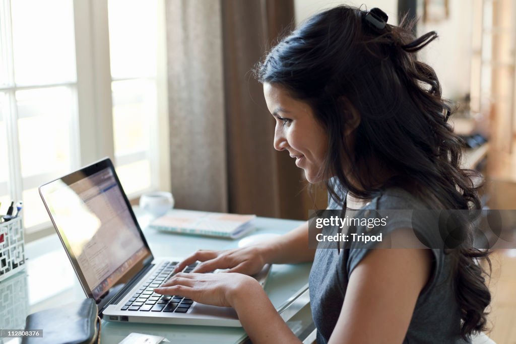 Woman working on laptop by window