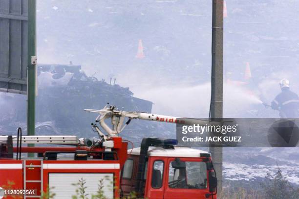 Les pompiers s'affairent, le 25 juillet 2000 à Gonesse, près de la roue du Concorde Air France qui s'est écrasé près de l'aéroport parisien de...