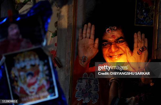 An Indian devotee gives offerings infront of a portrait of Satya Sai Baba as she prays for his speedy recovery, at the Puttaparthi village around 200...