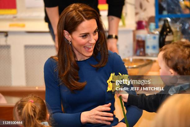 Britain's Catherine, Duchess of Cambridge receives a bunch of daffodils from a small child during a visit to St Josephs Sure Start Facility in...