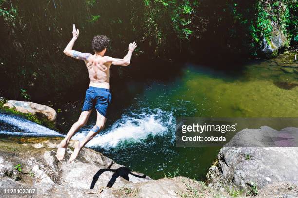 young man jumping from a waterfall at lumiar/rj - spring flowing water stock pictures, royalty-free photos & images