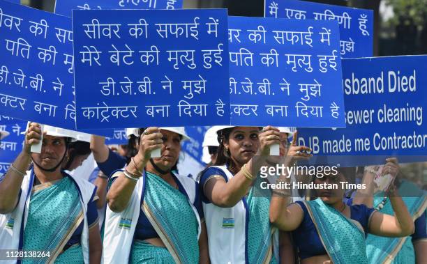 Family members of manual scavengers who died during their work seen with placards during the inauguration of specially fabricated sewer cleaning...