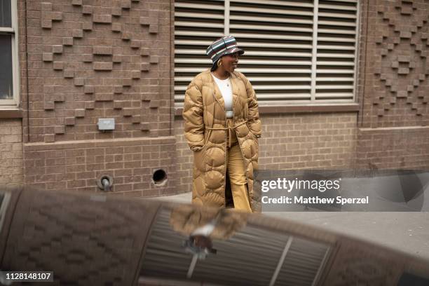 Guest is seen on the street during New York Fashion Week AW19 wearing quilted down gold coat with gold pants and striped hat on February 07, 2019 in...