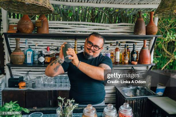 bartender mixing a drink in open air bar - bar man t shirt stock-fotos und bilder