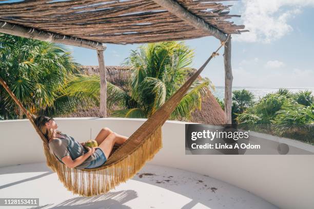 woman in hammock holding coconut - protection luxe stockfoto's en -beelden