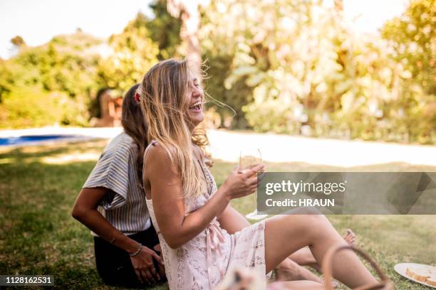 cheerful female friends with drinks sitting in yard - drinking in yard stock pictures, royalty-free photos & images