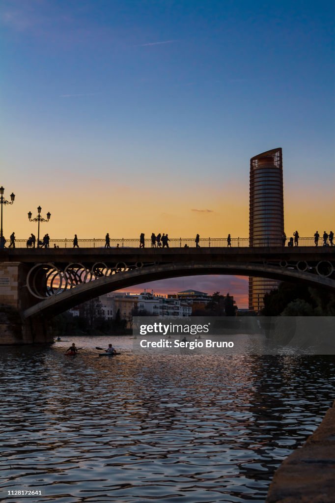 Torre Sevilla and Guadalquivir river at sunset with canoeists