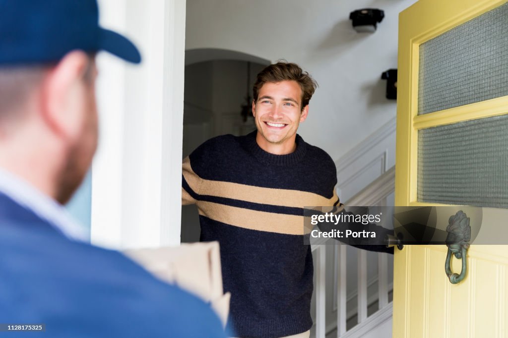 Happy man looking at delivery person at doorway