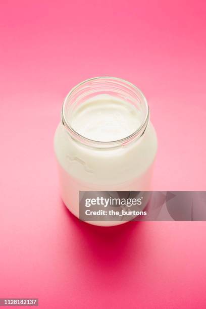 still life of plain white yogurt in glass jar on pink background - laktose photos et images de collection