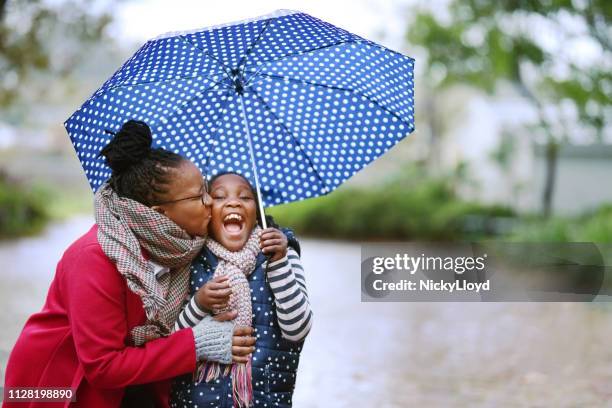 regen will nicht den tag verderben. - mother and daughter kiss happy stock-fotos und bilder