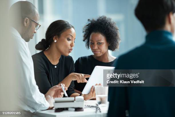 group of co-workers standing around desk and having meeting - young businessman digital tablet stockfoto's en -beelden