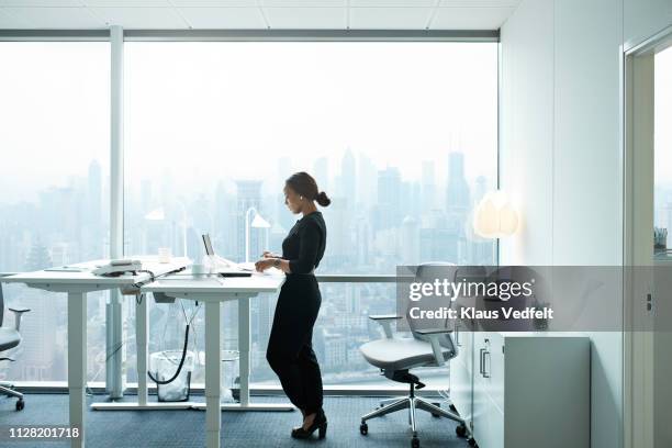 businesswoman working on computer in office with beautiful view of skyline - design laptop woman stock-fotos und bilder