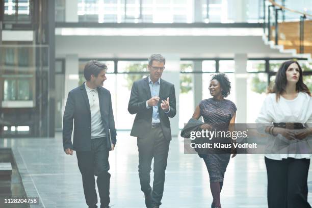 business people walking and talking inside moderne office building - atrio fotografías e imágenes de stock