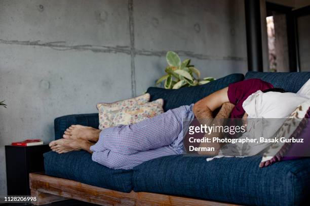 a man lying down on a sofa, sleeping - illness stock-fotos und bilder