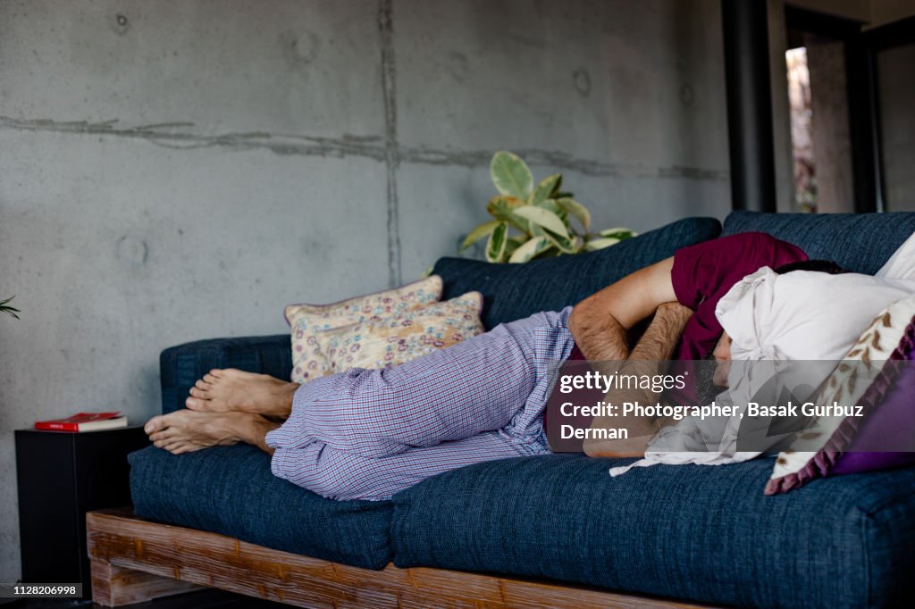 A man lying down on a sofa, sleeping