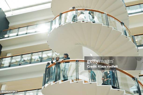 business people having discussion on staircase in modern office building - atrio-característica-arquitectónica fotografías e imágenes de stock