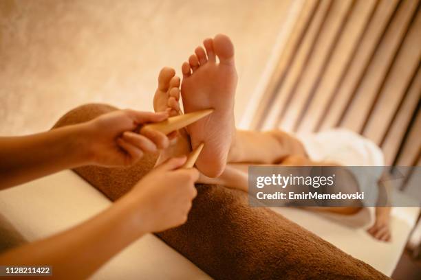 jonge vrouw met ontspannende voetmassage in beautysalon - voetzool stockfoto's en -beelden