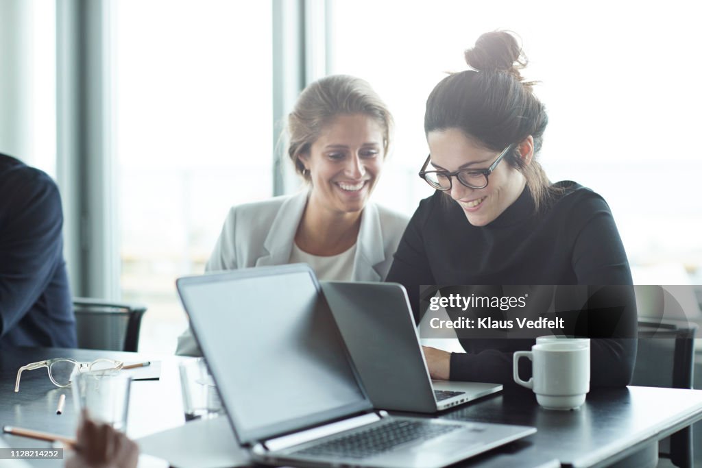 Co-workers having meeting with laptop in conference room