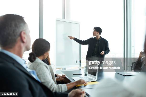 businessman doing presentation in big boardroom - men and women in a large group listening stock-fotos und bilder