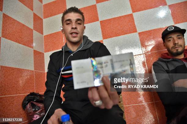 Young Algerian holds a banknote in the capital Algiers on February 28, 2019. - Tens of thousands of young Algerians across the country recently took...