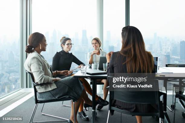 group of businesswomen having meeting in boardroom with stunning skyline view - corporate skyline stock pictures, royalty-free photos & images