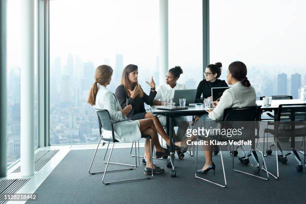 group of businesswomen having meeting in boardroom with stunning skyline view - only women stock-fotos und bilder