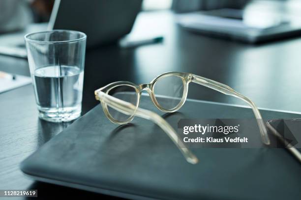 close-up of spectacles and glass of water on table in meeting room - water glasses ストックフォトと画像