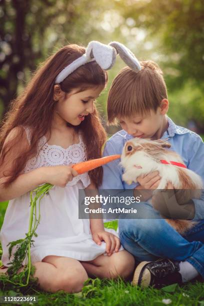 happy children playing with bunny on easter egg hunt - easter bunny stock pictures, royalty-free photos & images