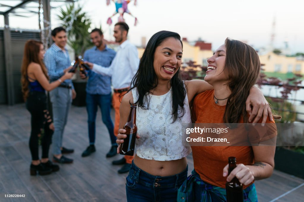 Latinx / Hispanic friends at party on the rooftop in the evening in summer