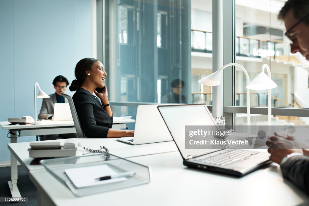 Businesswoman talking on smartphone in open office