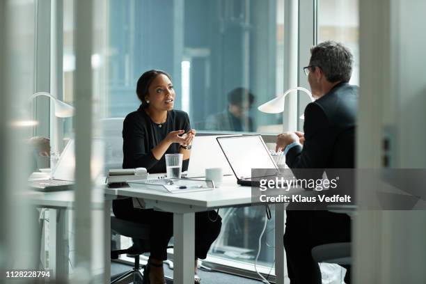 businesswoman speaking with co-worker in open office - see no evil hear no evil speak no evil fotografías e imágenes de stock