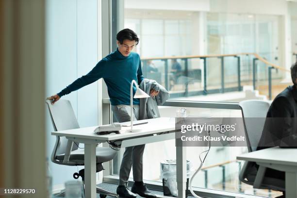 young businessman airing at desk in open office - coming home door stockfoto's en -beelden