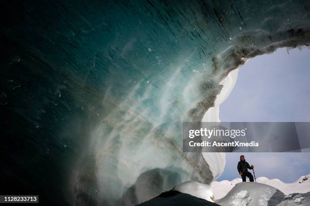 man exploring a stunning glacial ice cave - ice cave stock pictures, royalty-free photos & images