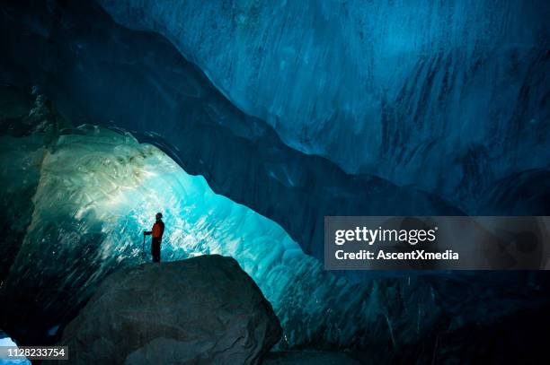 man exploring a stunning glacial ice cave - ice cave stock pictures, royalty-free photos & images
