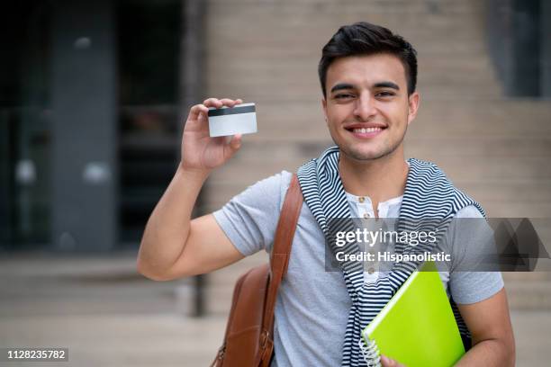 feliz joven hombre estudiante sosteniendo una tarjeta para editar sonriendo a cámara - identity card fotografías e imágenes de stock