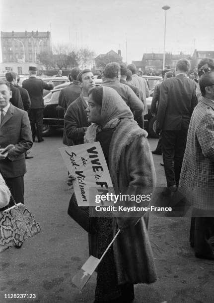 Drapeau du FLN dans une main et pancarte dans une autre, cette femme est venue accueillir la délégation du Vietcong, à Paris, France, le 4 novembre...