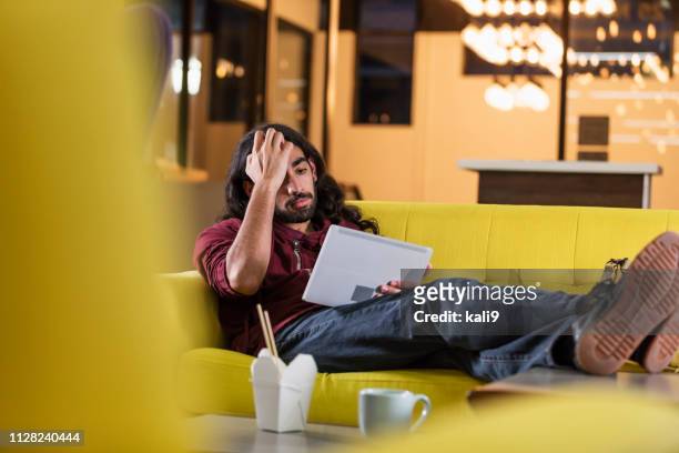 gemischte rassen mann auf sofa, mit digital-tablette in der nacht - zurücklehnen stock-fotos und bilder