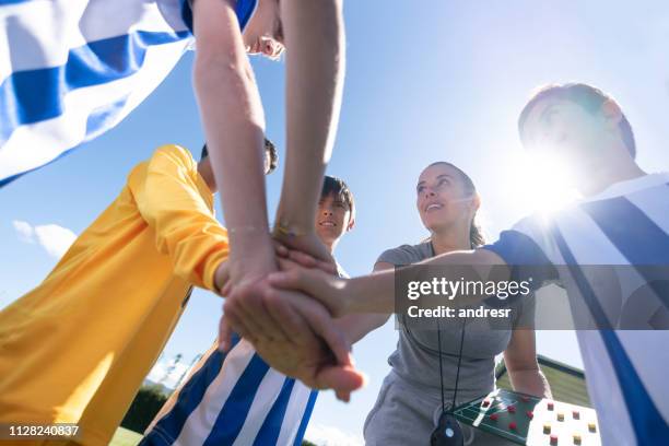 female soccer coach putting hands together in the middle with her team - soccer mom stock pictures, royalty-free photos & images