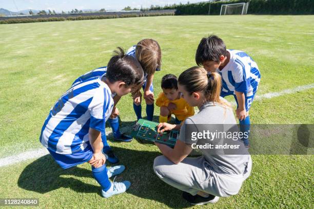 mom coaching a group of kids in summer soccer camp - soccer mom stock pictures, royalty-free photos & images