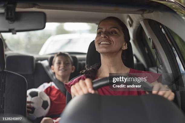 gelukkig soccer mom vervoer van kind naar voetbal praktijk in haar auto - familie sport stockfoto's en -beelden