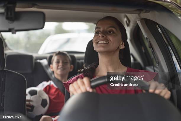happy soccer mom transporting kid to football practice in her car - practicing stock pictures, royalty-free photos & images