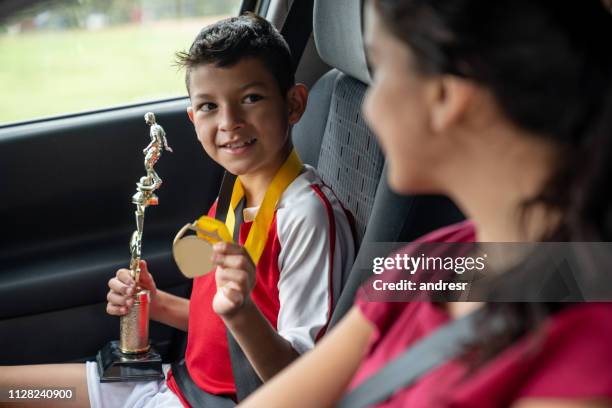 happy boy showing his mother the trophy he got playing football - soccer mom stock pictures, royalty-free photos & images