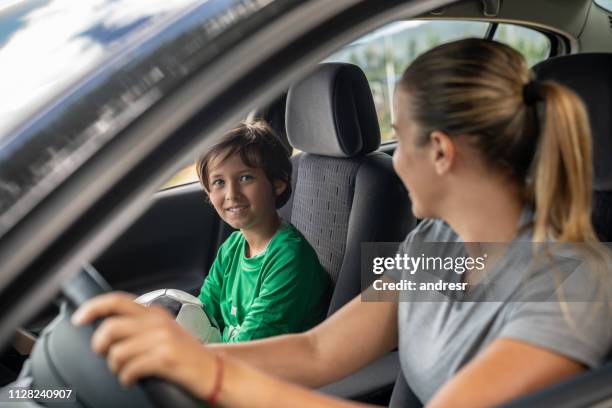 happy soccer mom transporting her son to football practice in her car - soccer mum stock pictures, royalty-free photos & images